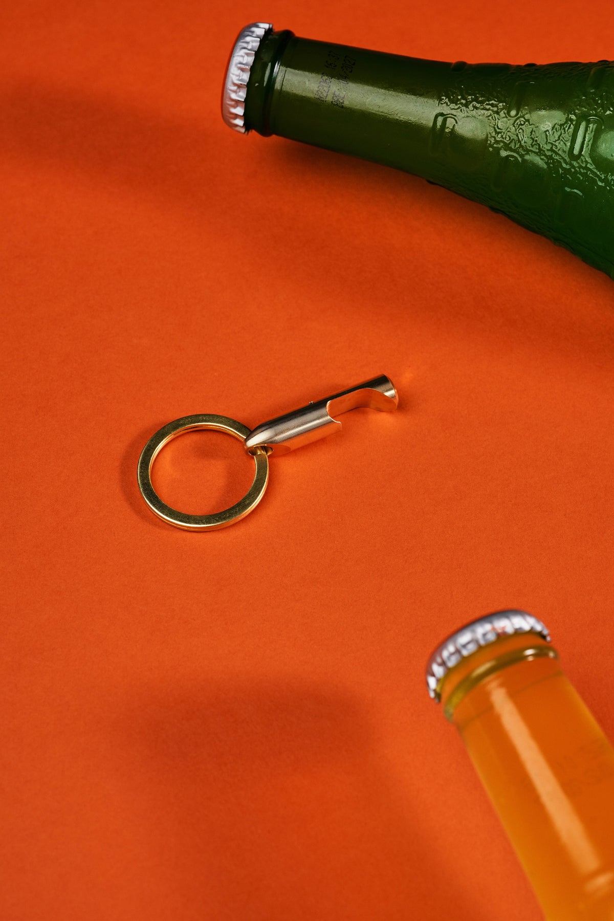 Bottle Opener - Brass on its key ring beside a bottle