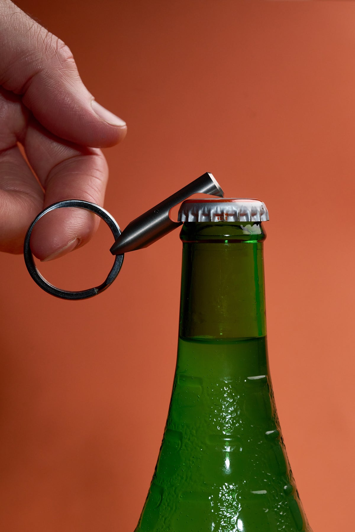 Bottle Opener - Titanium lifting the cap off a bottle