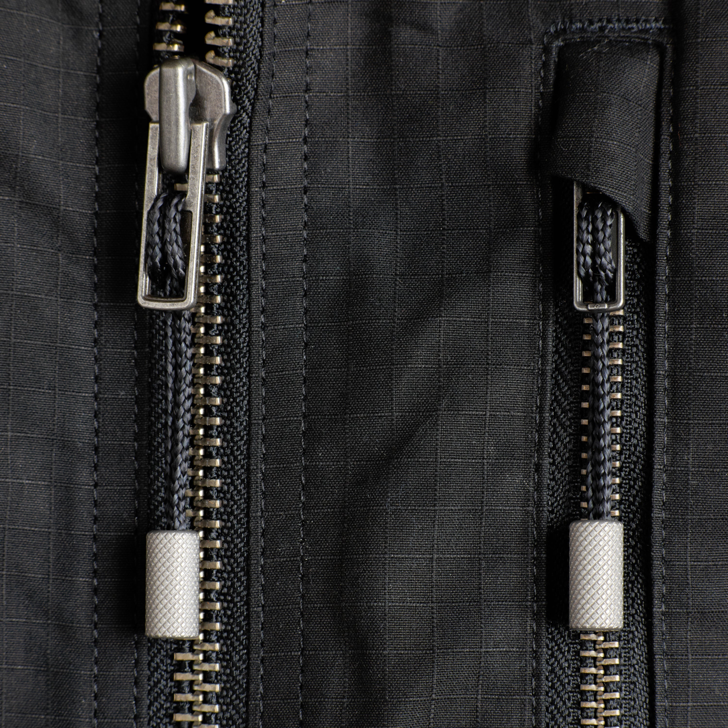 Close-up of a black jacket with steel zippers and pullers.