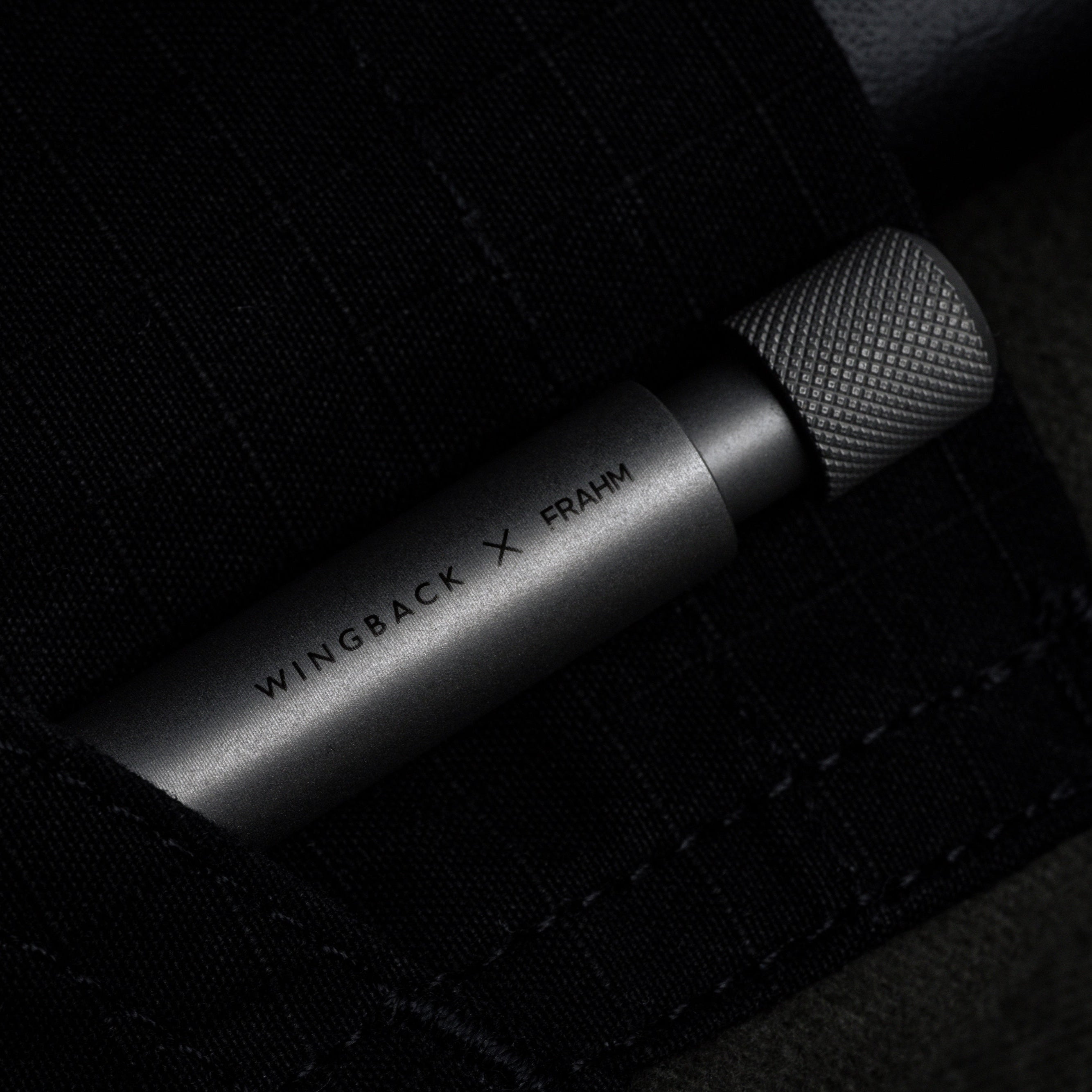 Metal pen with 'WINGBACK X' branding on a dark textured background