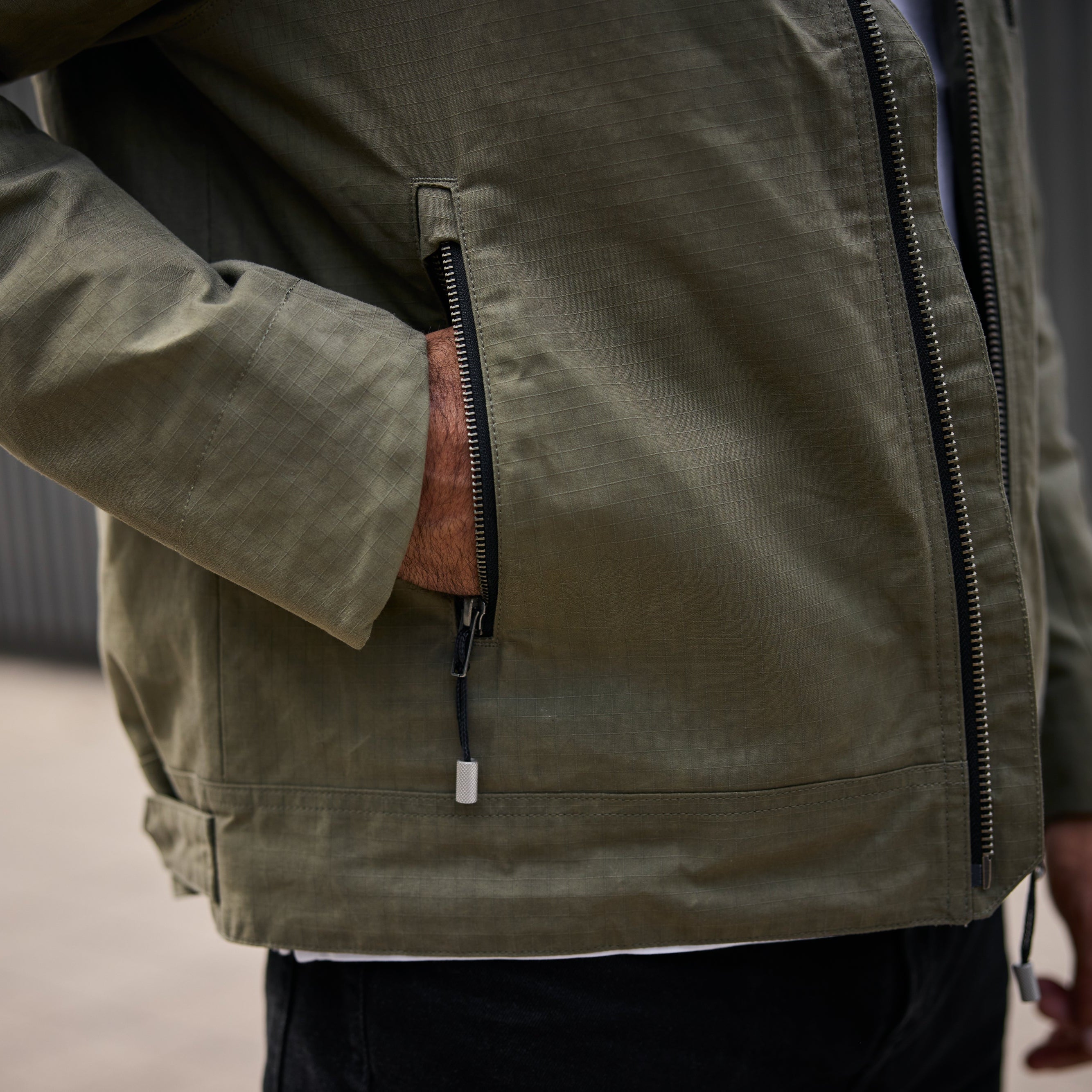 Person wearing a green jacket with a zipper detail on a blurred background