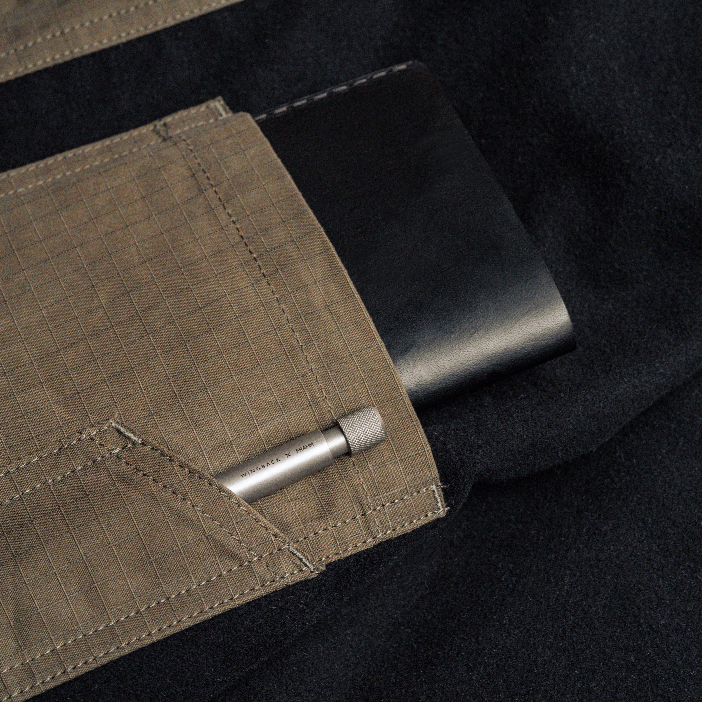 Close-up of a pocket on a dark jacket with a Wingback pen inside.