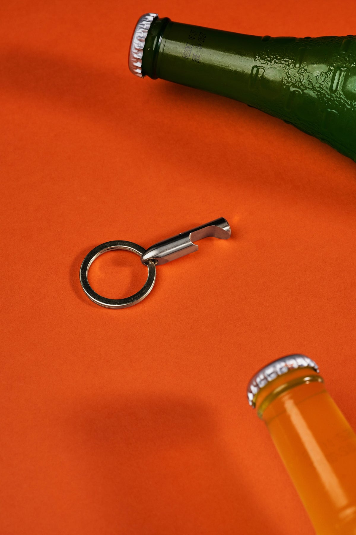 Bottle Opener - Titanium on its key ring beside a bottle
