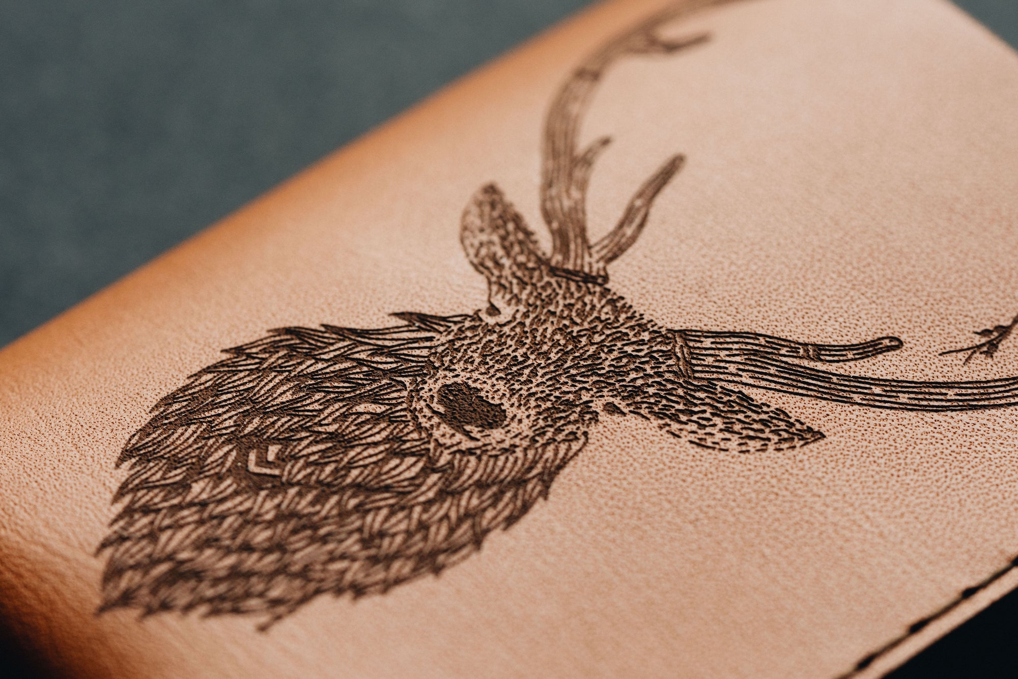 Detail of a red stag engraved in a Wingback wallet as part of a collaboration with Ollie Smither aka Os Illustration