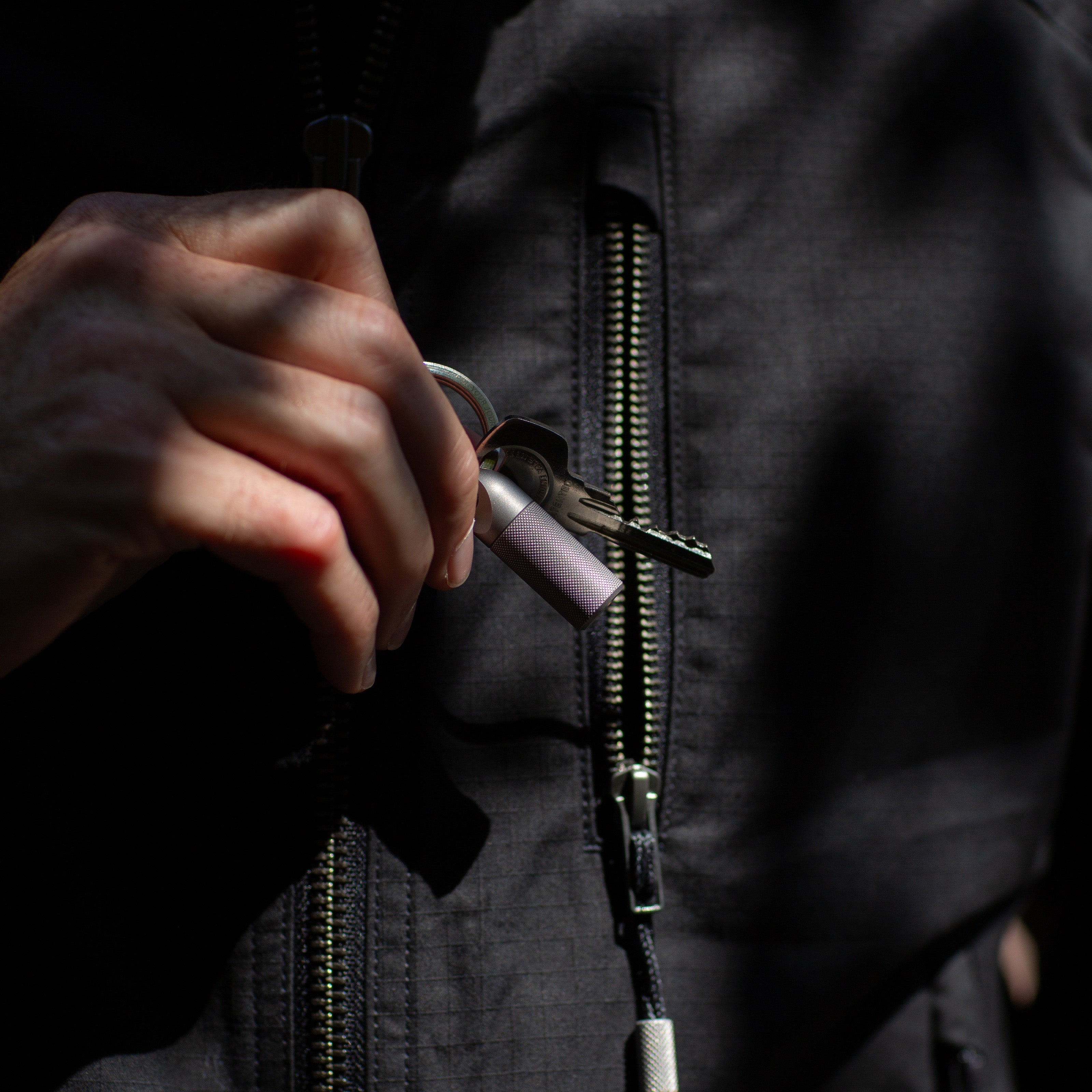 Hand holding a key with a dark jacket zipper in the background