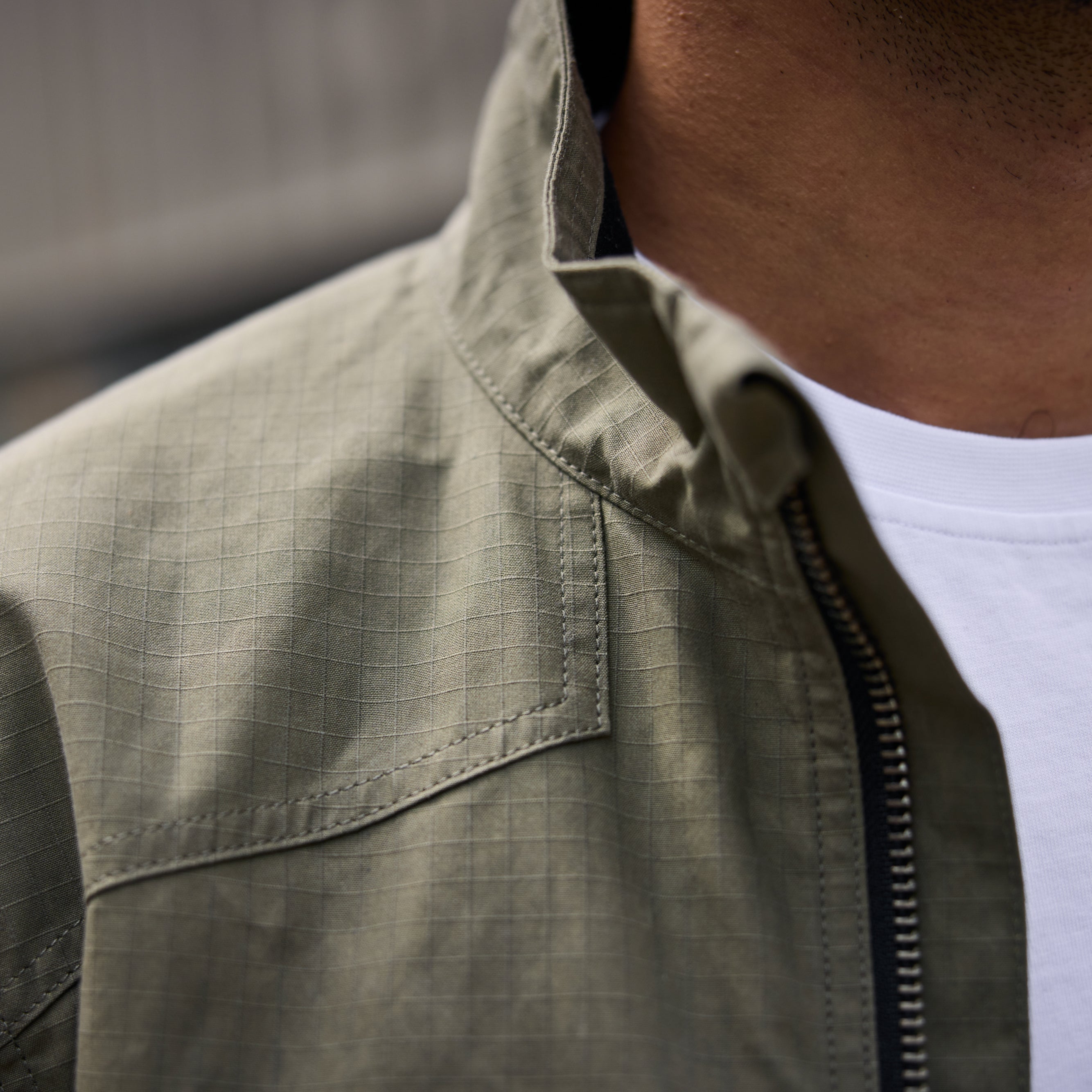 Close-up of a person wearing a green jacket with a blurred background