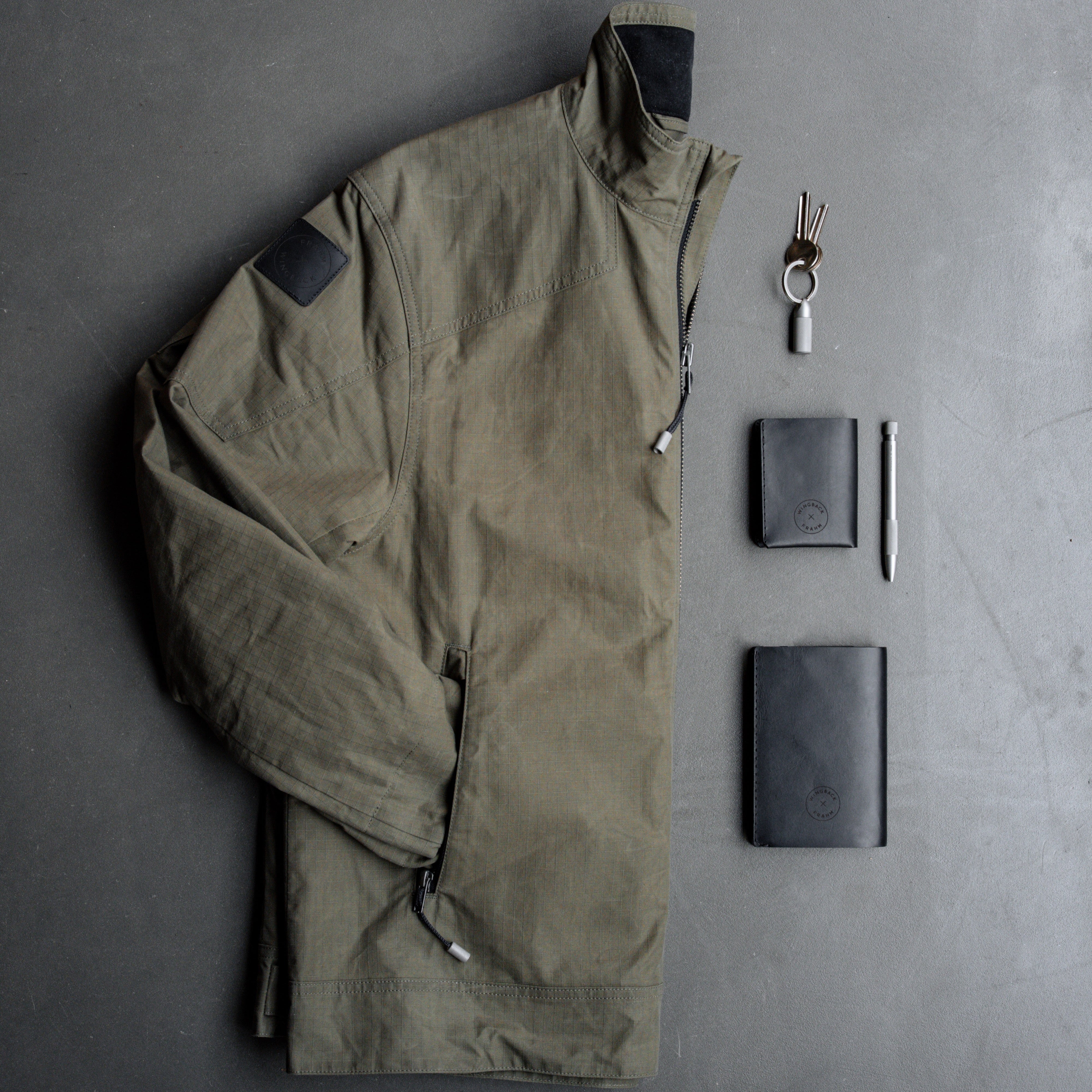 Green jacket and black accessories on a gray surface